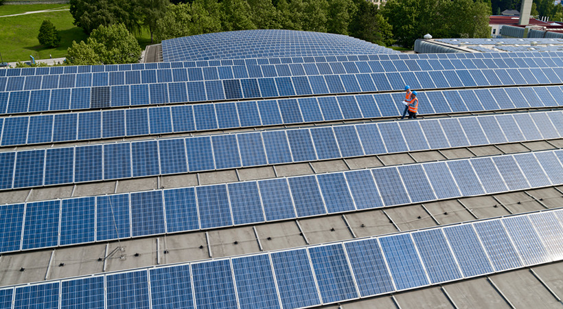 Seven rows of rooftop solar panels with more in the background.