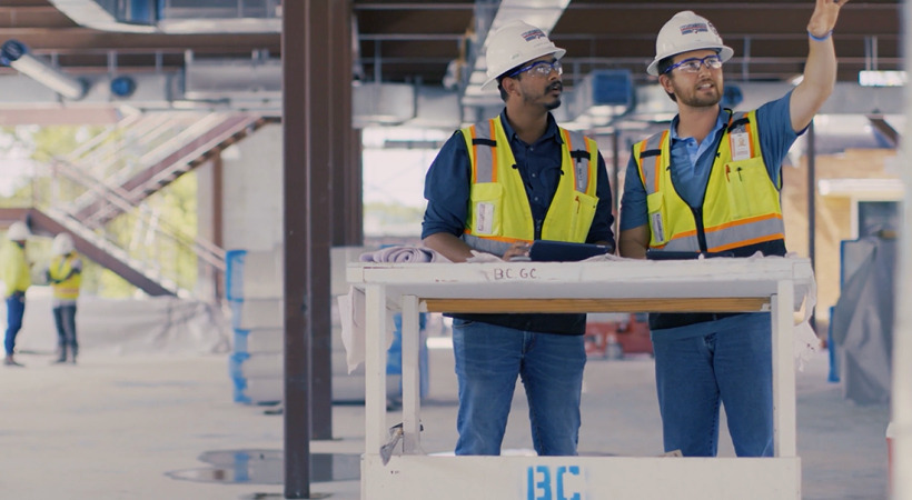 Two men in yellow vests and white hard hats stand at a drafting table. Image 5: Georgia-Pacific Building Products team members.