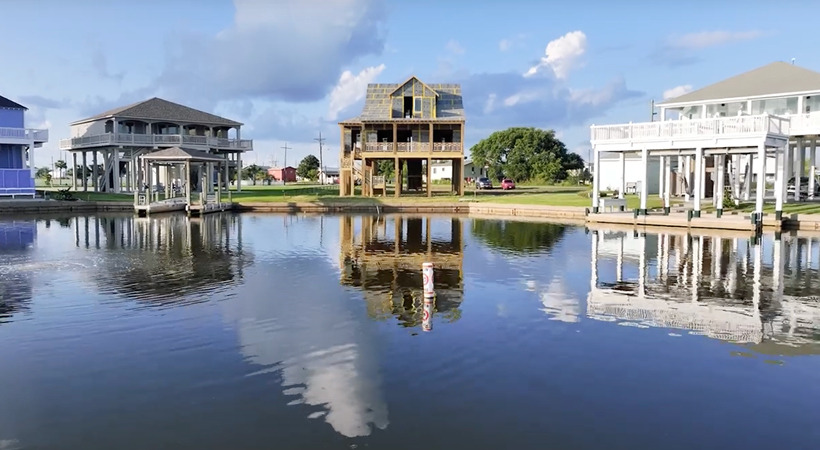 Vacation homes on an intracoastal waterway, sitting on pilings. The center home is under construction, sheathed in ForceField® Weather Barrier System.