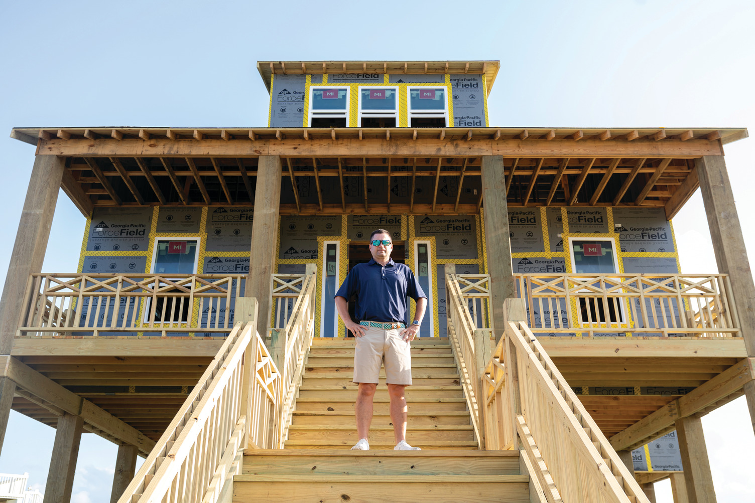 A man wearing a blue polo presses on ForceField® Premium Tape installed on a home.