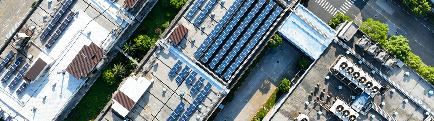 Aerial view of commercial slow-slope rooftops with solar panels installed. 